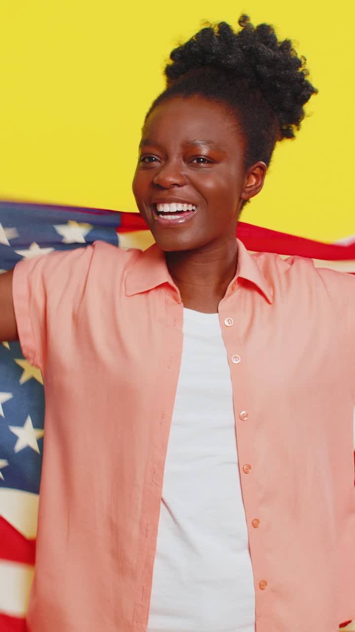 Giovane donna di colore che saluta e si avvolge nella bandiera americana, celebrando i diritti umani e le libertà