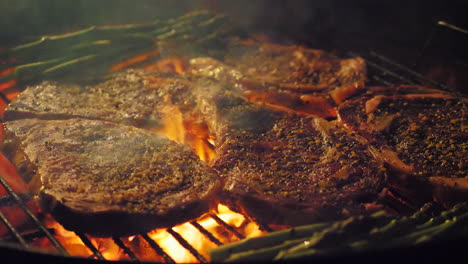 close up on steaks and asparagus cooking on a grill