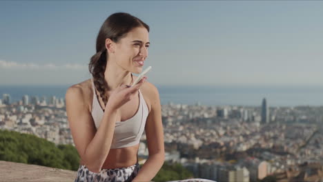 mujer en forma sonriente grabando un mensaje de voz en un teléfono inteligente en la ciudad de barcelona