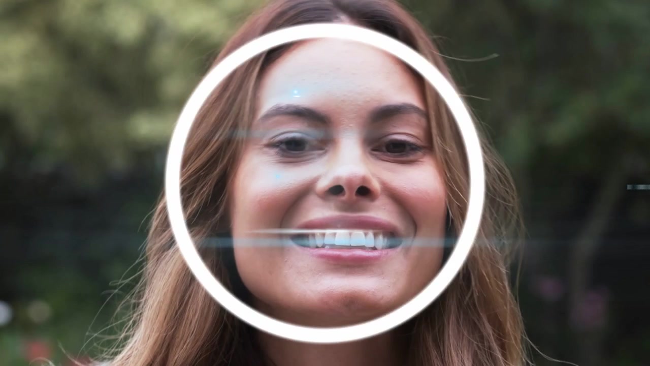 Woman in park glancing upward and smiling, initiating HUD rings pulsing across face, showing AR