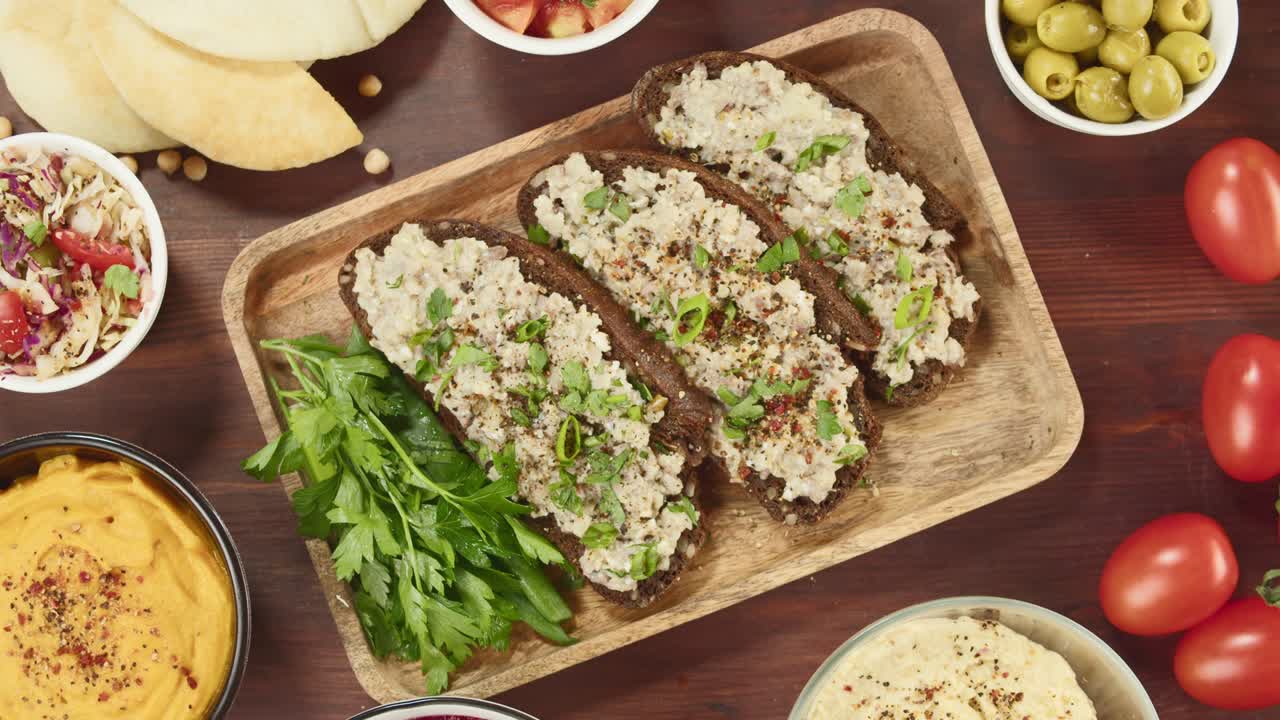 cocina israelí. forshmak con pan de centeno negro decorado con perejil, manos poniendo salsas vista superior. plato nacional de arenque judío, cultura de oriente medio. bocadillo vorschmack hecho de filete de pescado