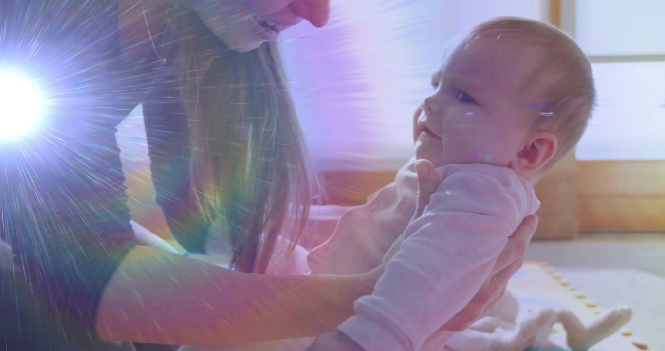 Una madre mette le mani sotto il bambino, sollevandolo per farlo sedere su un tappetino di schiuma, con un bagliore arcobaleno che supporta la salute.