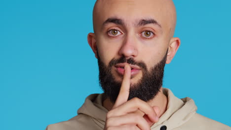 middle eastern person showing mute gesture with finger over lips