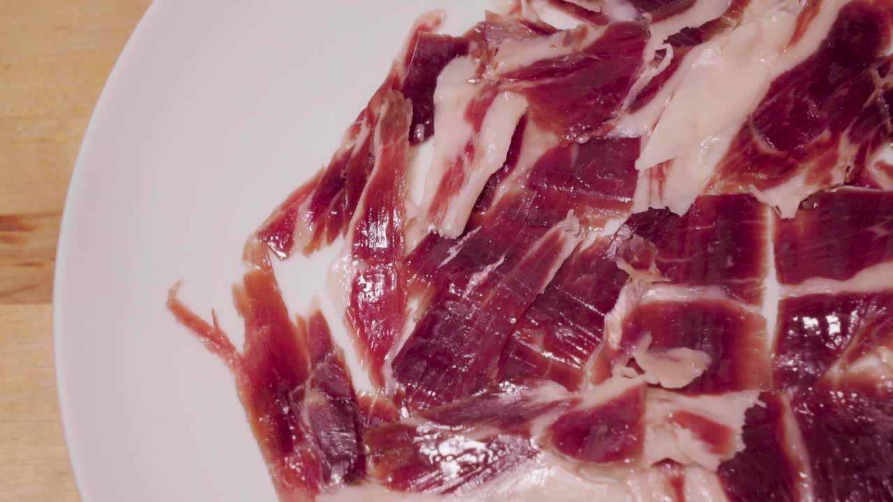 jamón ibérico español gourmet girando sobre un plato blanco con espacio para copiar a la izquierda
