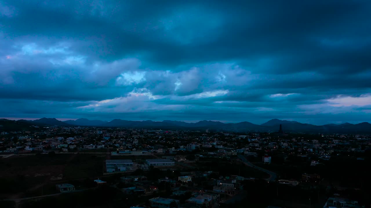 Città circondata da una catena montuosa con cielo nuvoloso e nuvole blu al tramonto