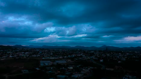 City-surrounded-by-mountain-range-with-cloudy-sky-with-blue-clouds-at-sunset