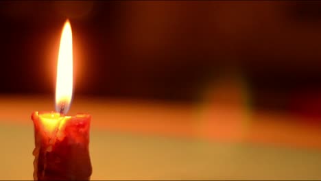 single candle flickers against dark background