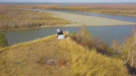 just married couple enjoys river view from hill aerial view