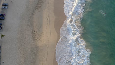 Sandy-Beach-Oahu-Hawaii-at-sunrise,-crashing-waves-and-walking-beachgoers