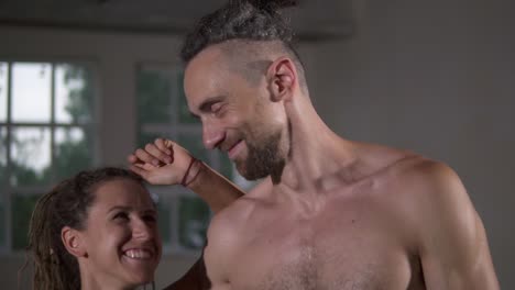 pareja feliz con rastas después de un entrenamiento exitoso en el club deportivo juntos. mujer deportiva mirando a su camiseta compañero guapo o entrenador, sonriendo el uno al otro abrazando