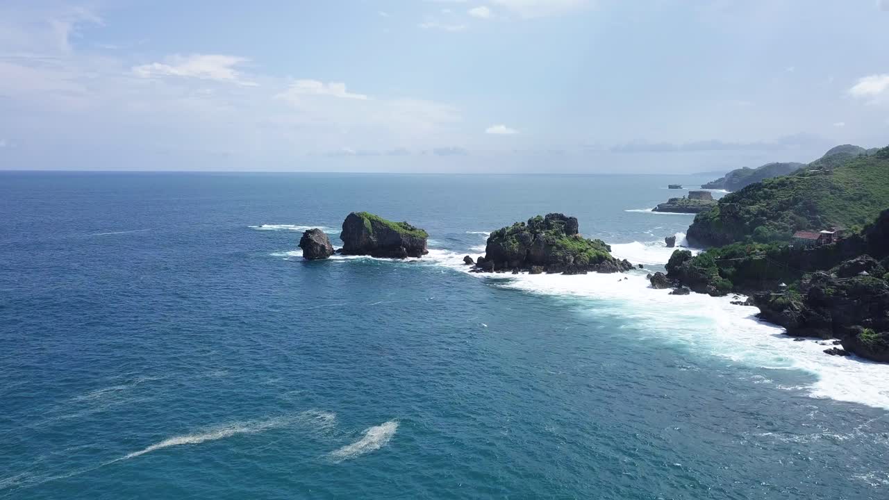 tiro de dron de dos islas rocosas en la playa, golpeadas por las olas durante el día soleado - isla timang, yogyakarta, indonesia