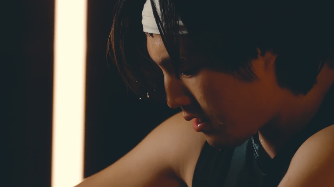 아시안 남자 운동선수 얼굴에서 이 흘러내리는 극단적인 4k 800fps 느린 동작, 어두운 체육관에서 근접 운동 후