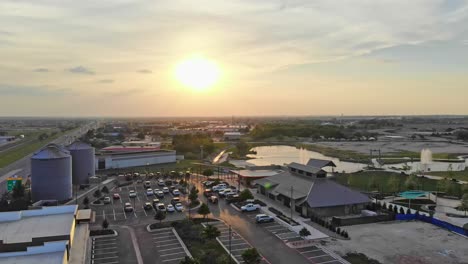 Moving-slowly-to-the-left-to-show-parking-lot-and-restaurants-that-features-iconic-gin-silos-as-part-of-a-downtown-development-with-pretty-sky-at-sunset