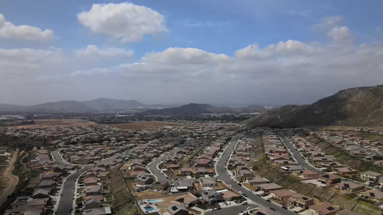 una toma de drone de un día nublado revela lentamente el mosaico de luz y sombra sobre un vecindario de riverside, california