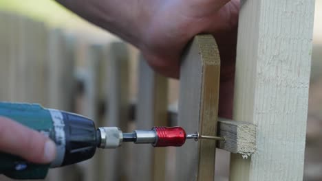 construcción de una cerca, primer plano de perforación en el tornillo final en una cerca de madera