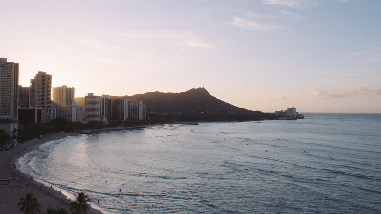 nascer do sol sobre a cabeça de diamante e edifícios de hotéis altos, raios de luz refletindo no mar, waikiki