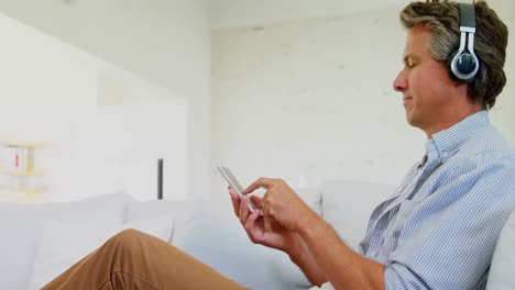 Man-listening-to-music-on-headphones-in-living-room-4k