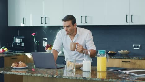 business man watching video big kitchen. shocked man looking at laptop computer