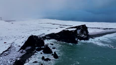 Meereswellen,-Die-Auf-Tufffelsen-Spritzen,-Die-Im-Winter-Mit-Schnee-Bedeckt-Sind