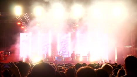 crowd at concert  and blurred stage lights of people dancing at the rock 'n roll concert.