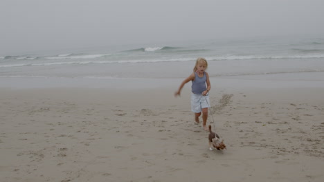 child running on the beach with a dog on a leash
