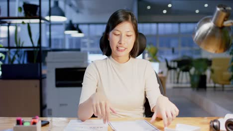 happy asian casual businesswoman with documents making video call, working late, in slow motion