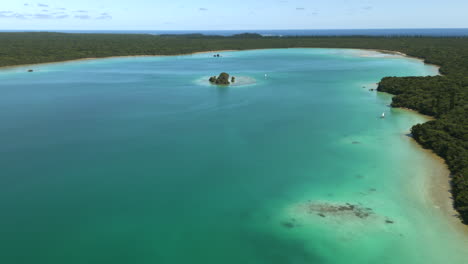 Piraguas-Tradicionales-En-Las-Aguas-Prístinas-De-La-Bahía-De-Upi,-Isla-De-Los-Pinos-En-Nueva-Caledonia---Revelación-Aérea-De-Retroceso