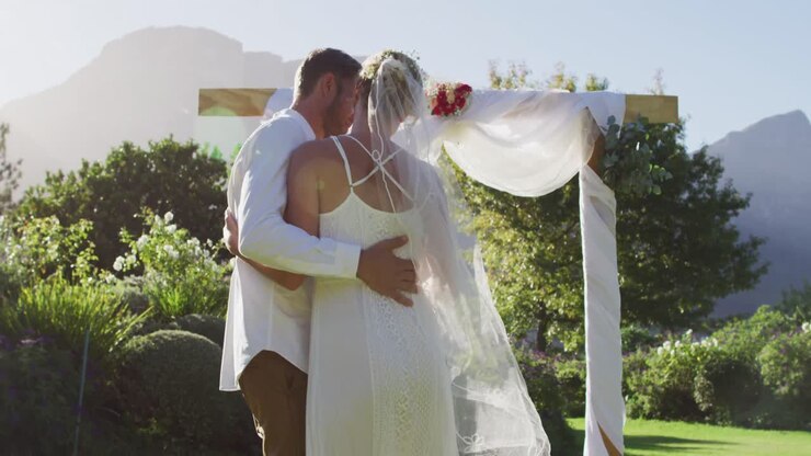 Portrait of happy caucasian newly wed couple, dancing in front of altar outdoors