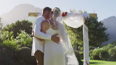 Portrait-of-happy-caucasian-newly-wed-couple,-dancing-in-front-of-altar-outdoors