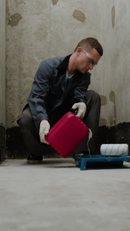 painter pouring paint from a can onto a tray