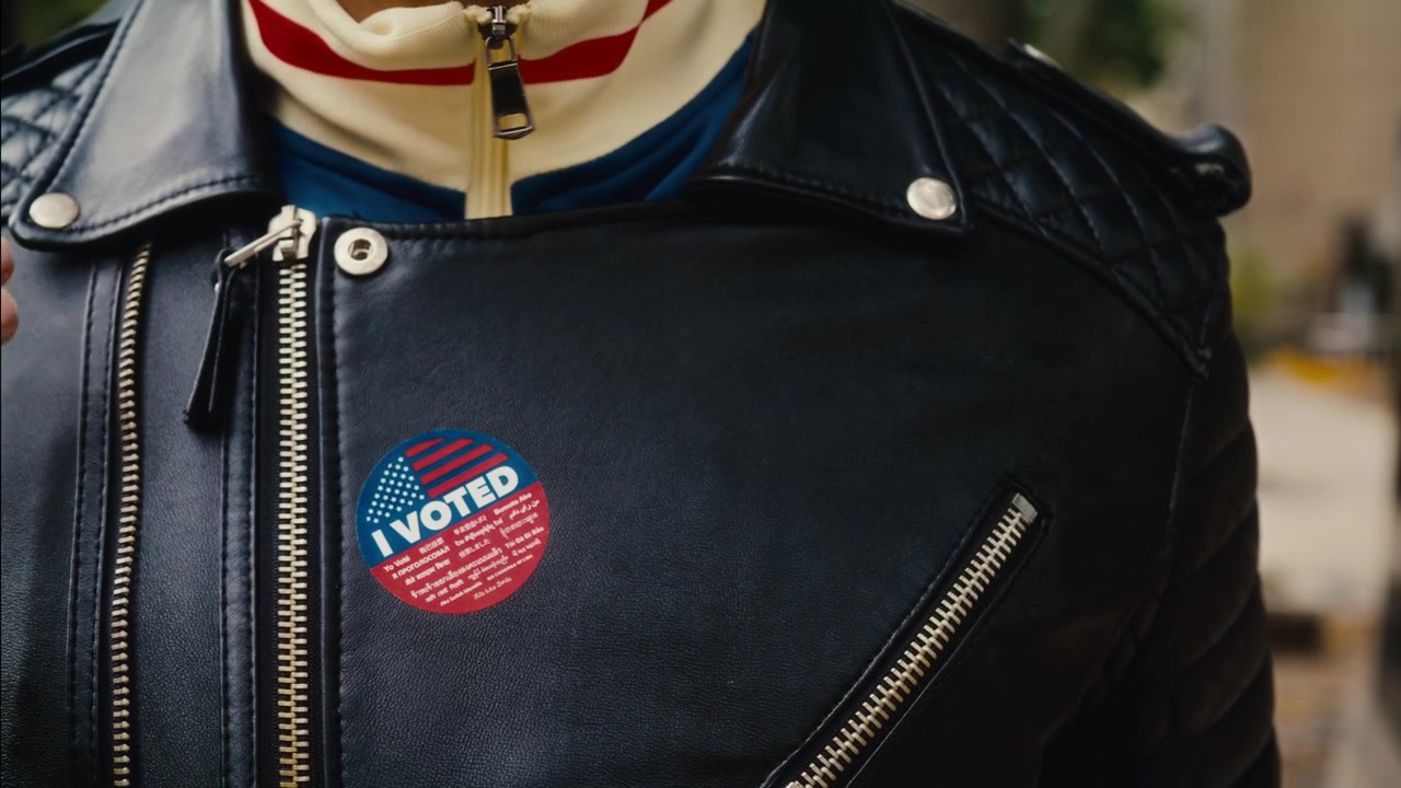 Latino man proudly putting 'I Voted' sticker on his jacket. Daylight Exterior