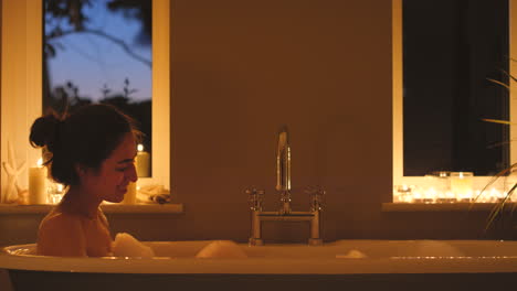 woman relaxing in a bubble bath at night