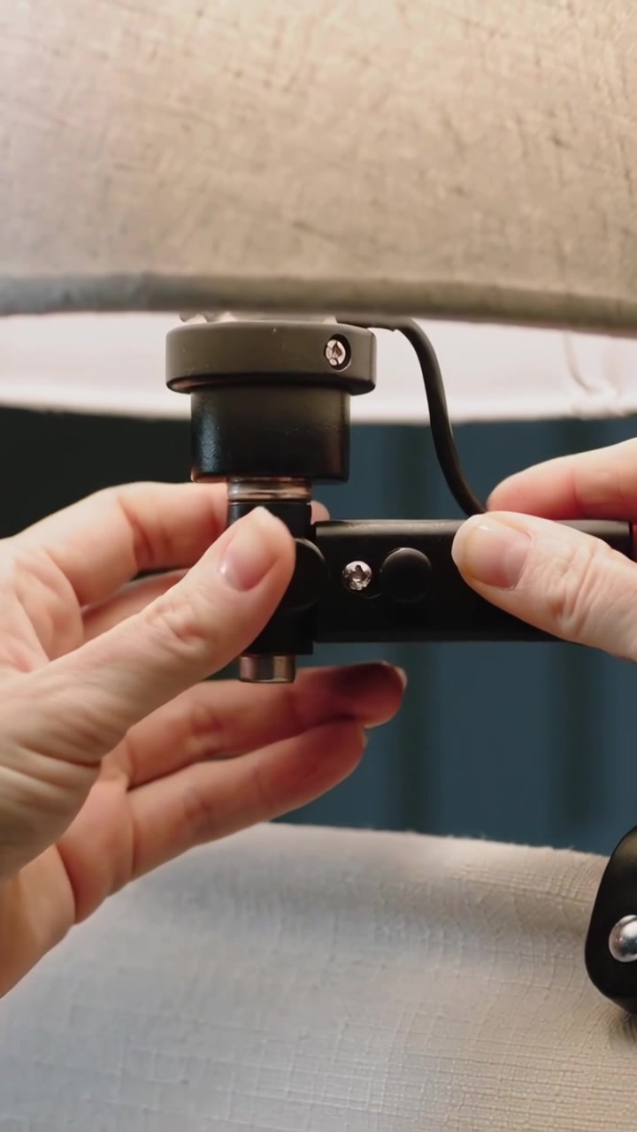 Vertical video: Reaching hands securing coupling under fabric lampshade at bedside, cord looping