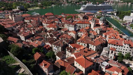 kotor old town with red rooftops, stone buildings, and cruise ship docked at the bay of kotor, montenegro.