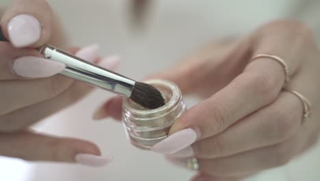 Carefully-slow-apply-glitter-to-brush-pulling-out-of-case---close-up-macro-of-hands-with-white-nails---cosmetic-skin-care