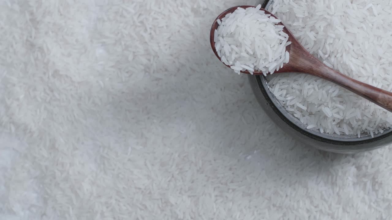 Raw Rice Grain In Bowl And Wooden Spoon Rotate In Slow Motion. White Rice Grains Food Background