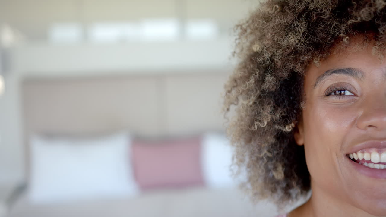 Smiling woman with curly hair in cozy home environment, feeling happy, copy space