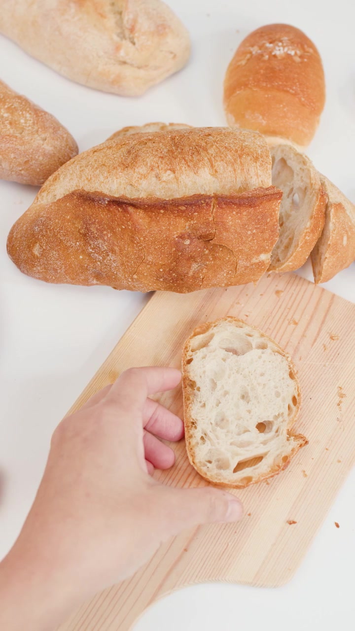 Hand Placing a Slice of Fresh Sourdough Bread on a Wooden Board