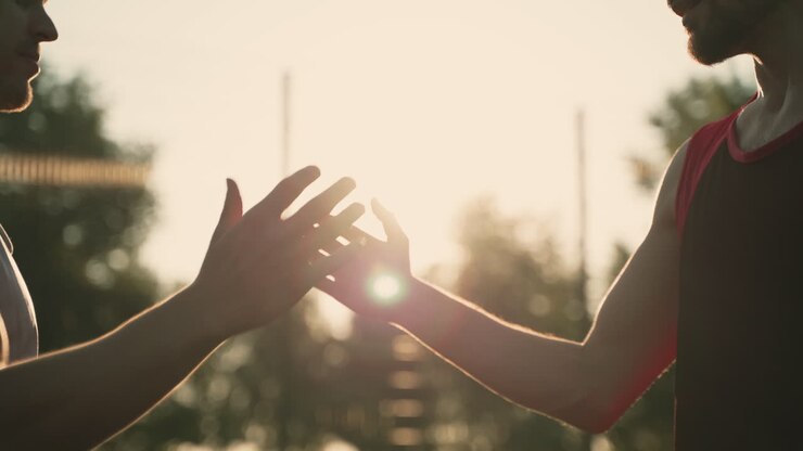Primo piano di un cordiale saluto tra due amici maschi in un parco al tramonto