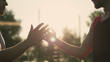 close up of friendly greeting between two male friends in a park at sunset