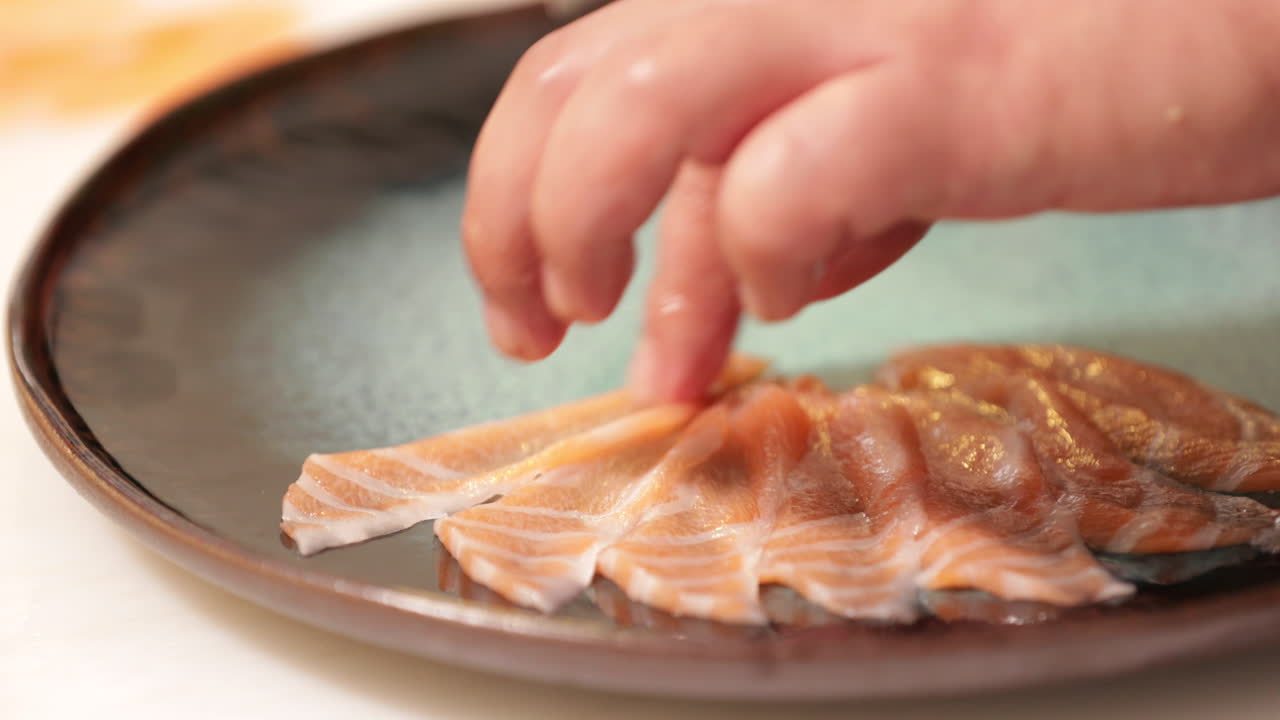 colocar rodajas finas de salmón crudo fresco en un plato - primer plano, cámara lenta