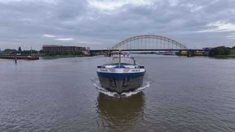 cargo ship on a river with a bridge