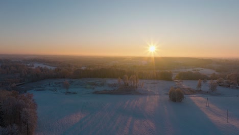 Luftaufnahme-Einer-Ländlichen-Landschaft-Im-Winter,-Schneebedeckte-Landschaftsfelder,-Kaltes-Frostwetter,-Sonnenuntergang-Mit-Goldenem-Stundenlicht,-Breite-Drohnenaufnahme,-Die-Sich-Vorwärts-Bewegt