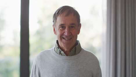 Portrait-of-happy-senior-caucasian-man-in-living-room-smiling-to-camera