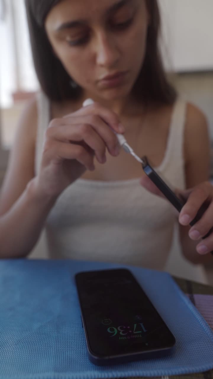 Giovane donna che pulisce la porta di ricarica dello smartphone con un piccolo attrezzo