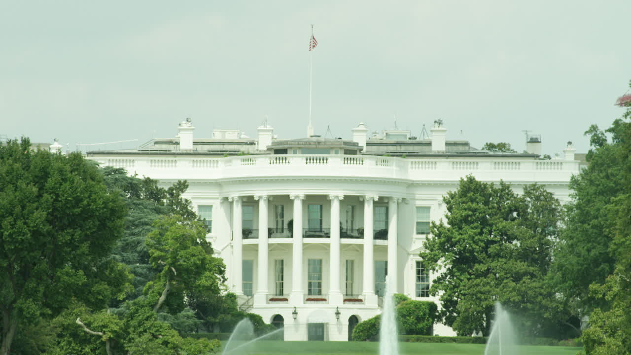 White House in Washington DC with American flag waving in the wind.