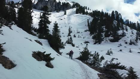 two persons man and woman hiking along an epic snow mountain panorama path high above scenic bavaria elmau castle and glacier peaks in the bavarian austrian alps on a cloudy and sunny day in nature