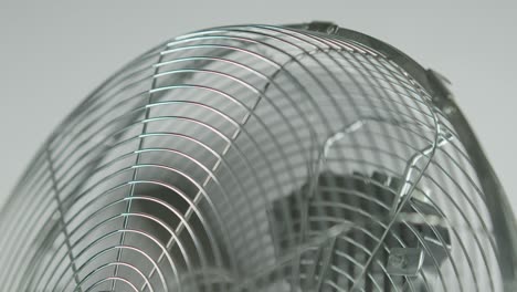 pale di ventilatore nero a movimento lento di un ventilatore metallico di fronte a uno sfondo bianco