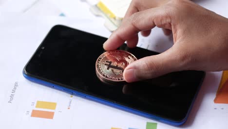 bitcoin coin on a smartphone with business documents