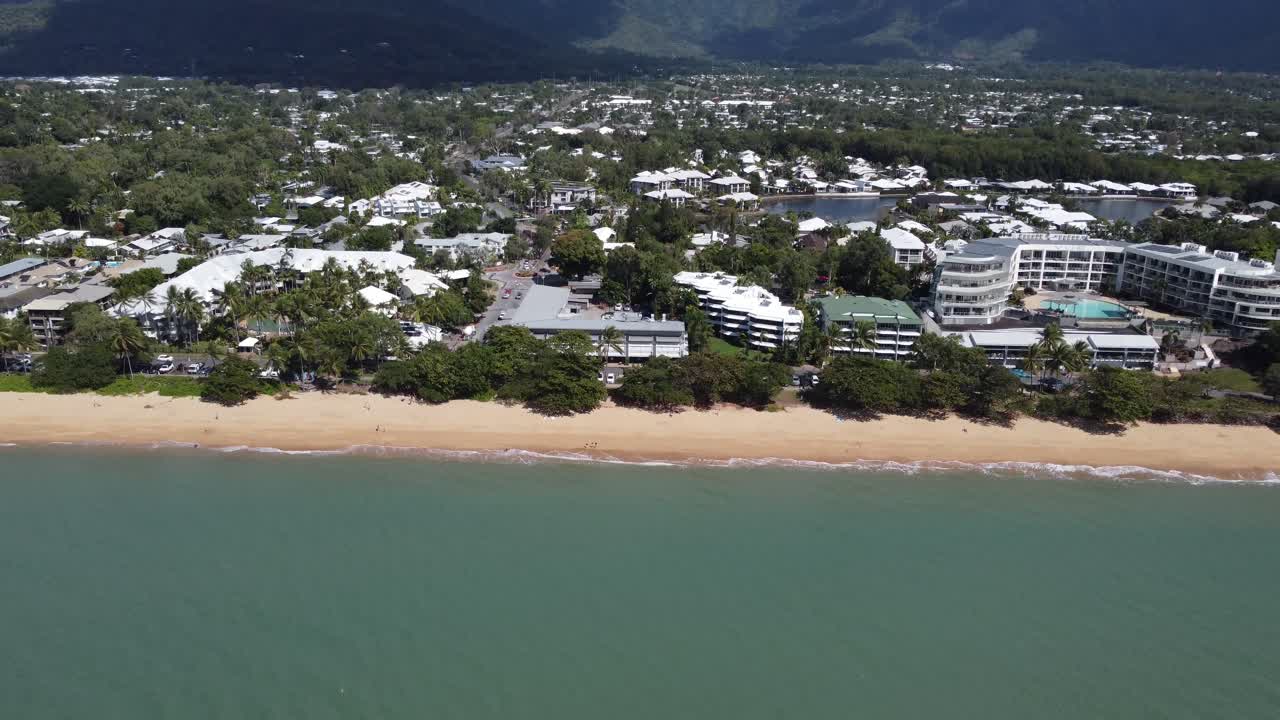 4K Aerial view of a beautiful sandy beach with a small seaside town and luxury hotels in North Queensland, Australia